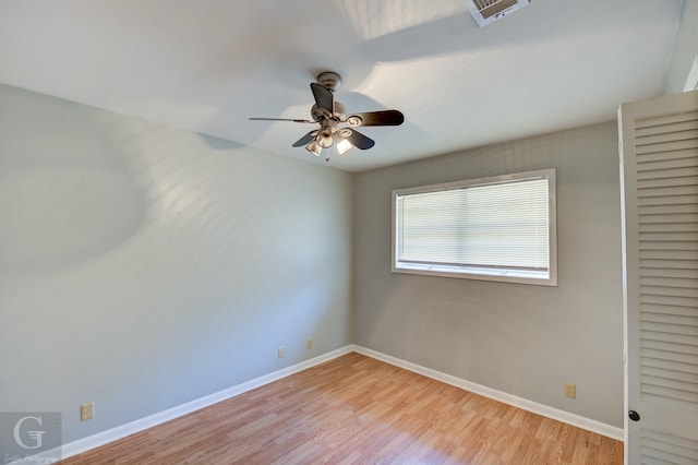 empty room featuring baseboards, ceiling fan, visible vents, and light wood finished floors