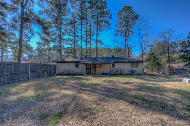 rear view of house featuring a fenced backyard, a lawn, brick siding, and central AC unit