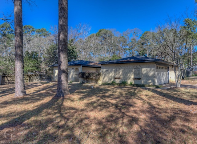 rear view of house with a yard, brick siding, and an attached garage