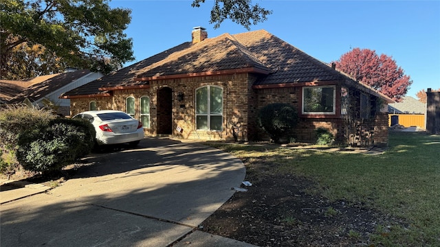 view of front of property with a chimney, a front lawn, and brick siding