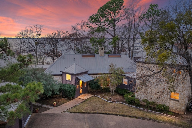 view of front of house featuring a standing seam roof, metal roof, and a chimney