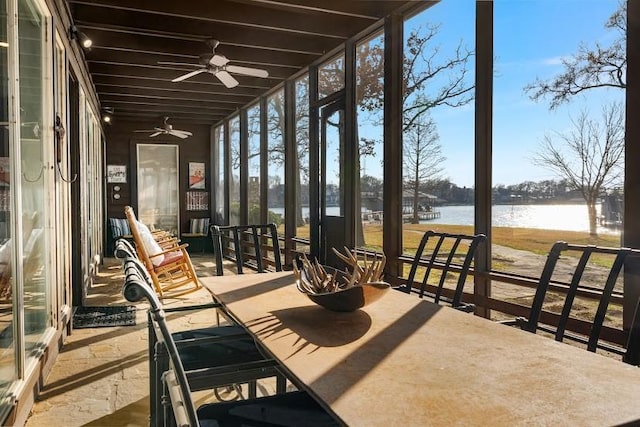 sunroom featuring a water view, a healthy amount of sunlight, and a ceiling fan