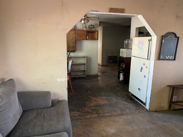 kitchen with concrete flooring, white appliances, brown cabinets, and ceiling fan