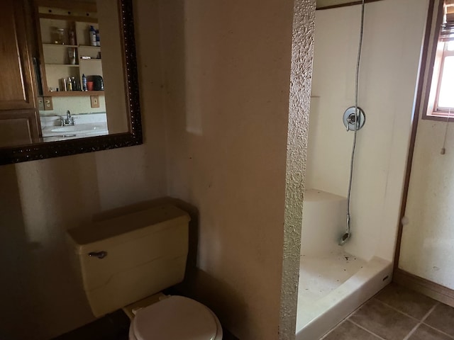 bathroom with a shower, toilet, and tile patterned floors