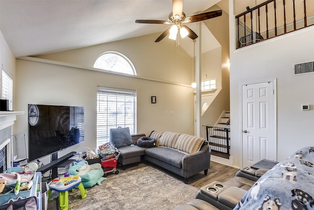 living area featuring ceiling fan, a fireplace, wood finished floors, visible vents, and stairs