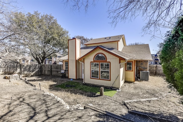 back of house featuring a shingled roof, a chimney, cooling unit, and a fenced backyard