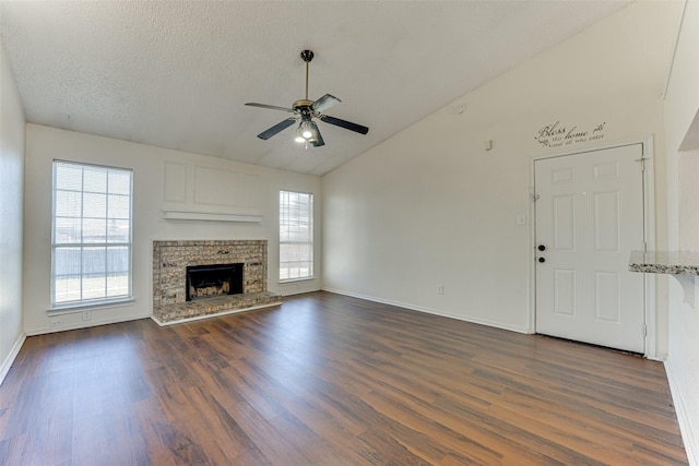 unfurnished living room featuring a textured ceiling, a fireplace, a ceiling fan, baseboards, and dark wood finished floors