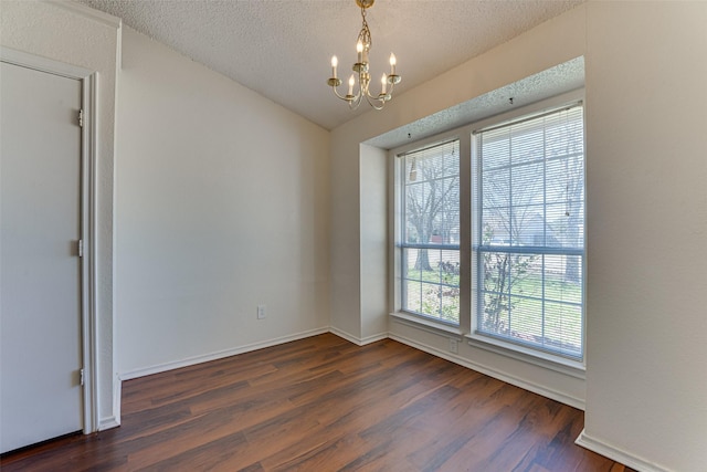 spare room featuring a chandelier, dark wood-style flooring, and a textured ceiling