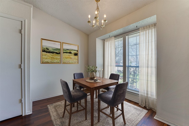 dining room with lofted ceiling, an inviting chandelier, dark wood-style floors, and a textured ceiling