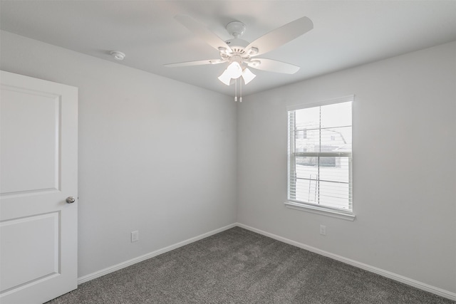 empty room featuring ceiling fan, dark carpet, and baseboards