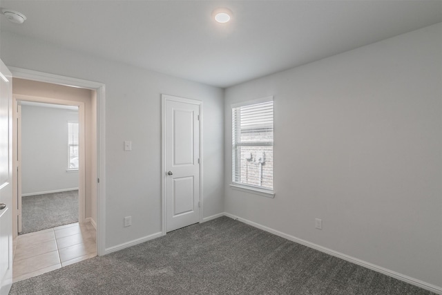 unfurnished room featuring carpet, baseboards, and tile patterned floors