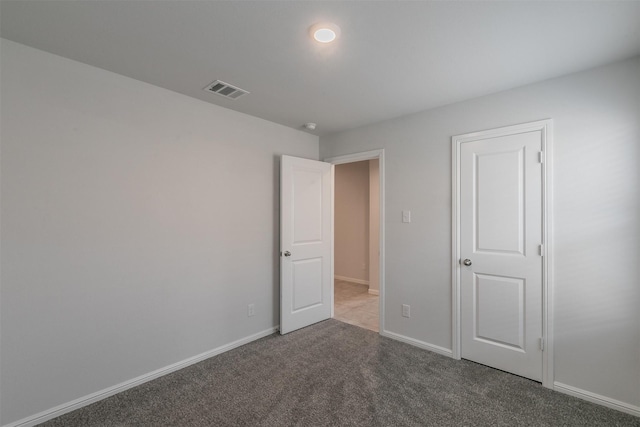 unfurnished bedroom with carpet, visible vents, and baseboards