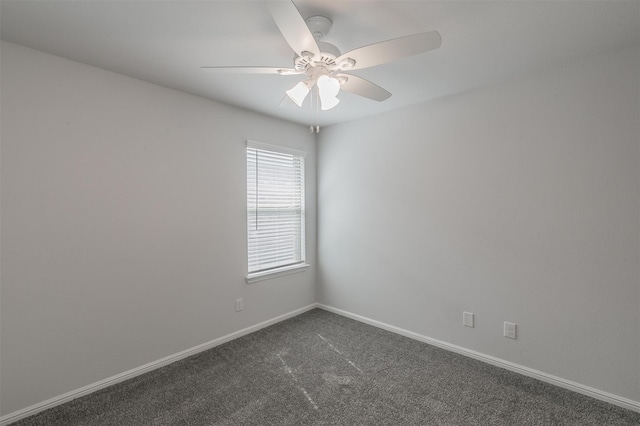 spare room featuring ceiling fan, dark colored carpet, and baseboards