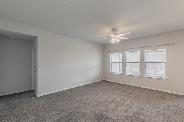 unfurnished room featuring ceiling fan, dark carpet, and baseboards