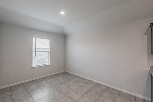 empty room with vaulted ceiling and baseboards