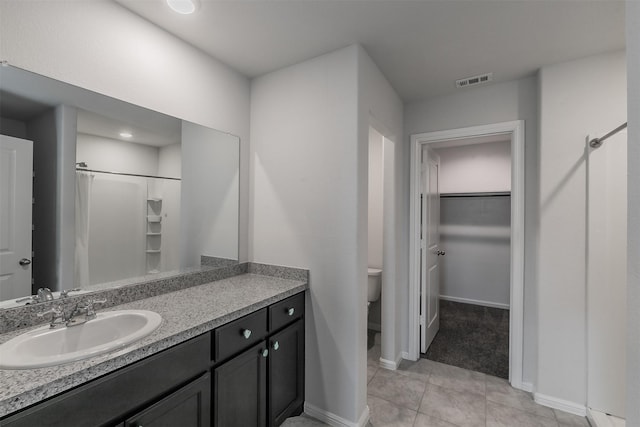 full bath with a walk in closet, visible vents, toilet, vanity, and tile patterned flooring