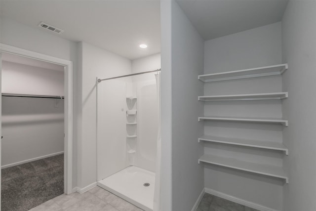 bathroom featuring a stall shower, baseboards, visible vents, and a walk in closet