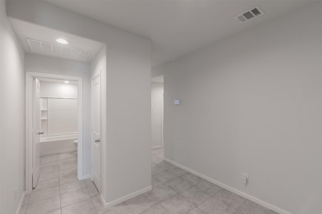 hall with visible vents, baseboards, and light tile patterned floors