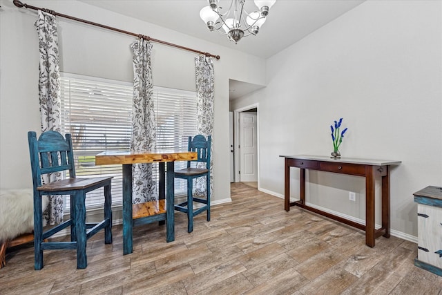 dining space featuring a chandelier, wood finished floors, and baseboards