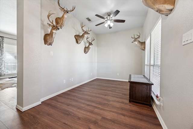 spare room featuring baseboards, visible vents, ceiling fan, and wood finished floors