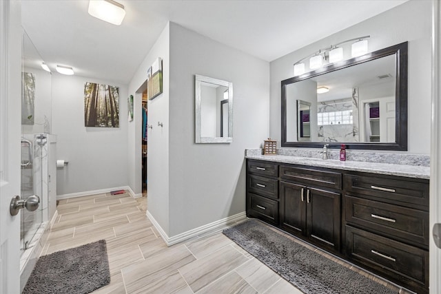 bathroom featuring walk in shower, vanity, and baseboards