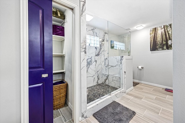 full bath featuring wood finish floors, baseboards, and a marble finish shower