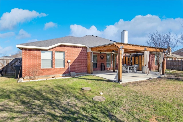 back of property featuring a patio, brick siding, fence, a yard, and a chimney