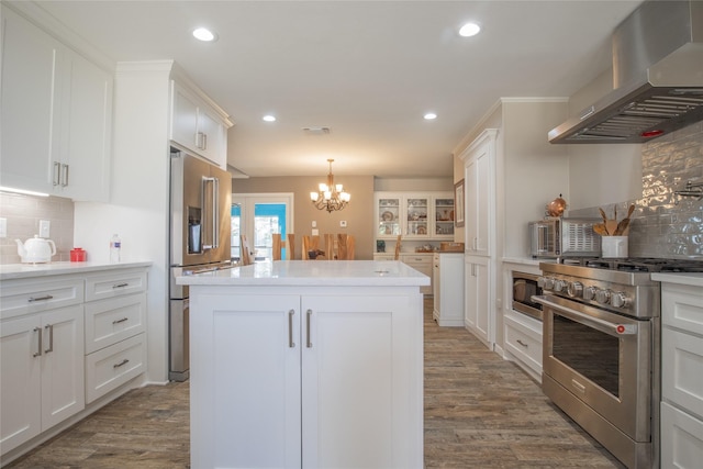 kitchen with white cabinetry, a kitchen island, wood finished floors, high quality appliances, and wall chimney exhaust hood