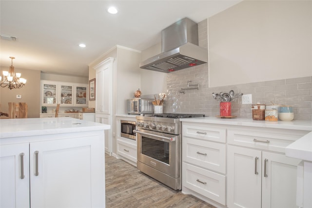 kitchen featuring tasteful backsplash, visible vents, appliances with stainless steel finishes, white cabinetry, and wall chimney exhaust hood