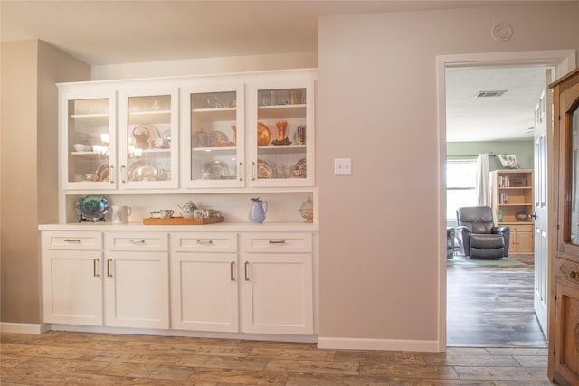 bar featuring light wood-type flooring, visible vents, and baseboards