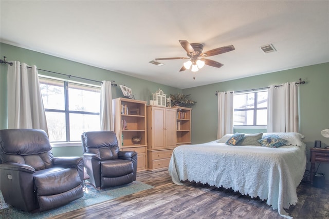 bedroom featuring a ceiling fan, multiple windows, visible vents, and dark wood-type flooring