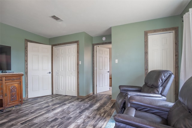 living area with wood finished floors, visible vents, and baseboards