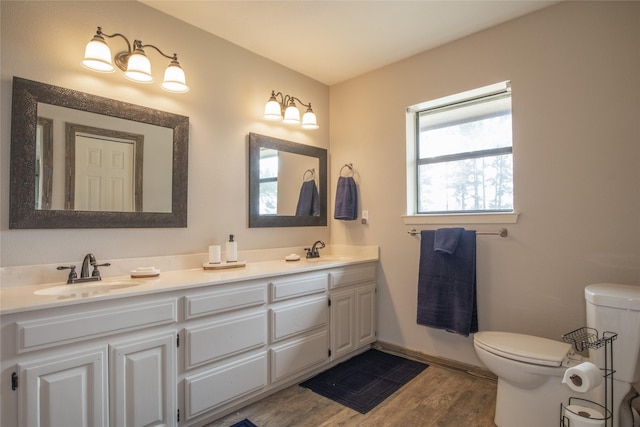 bathroom with toilet, double vanity, a sink, and wood finished floors