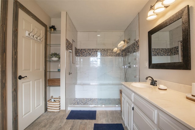 full bath featuring a tile shower, vanity, and wood finished floors