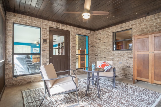 interior space featuring a ceiling fan, wood ceiling, and brick wall