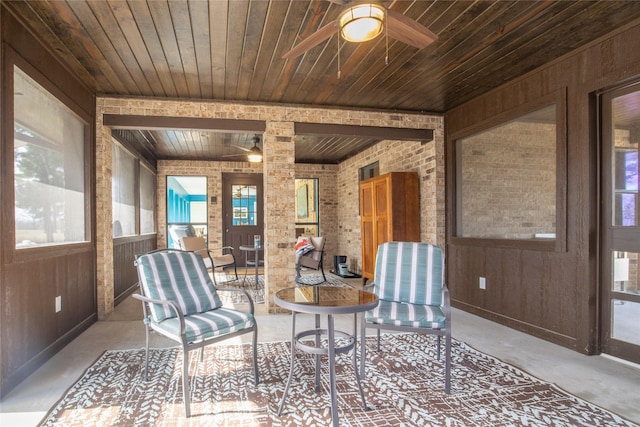 unfurnished room featuring concrete floors, wooden ceiling, ceiling fan, and wooden walls