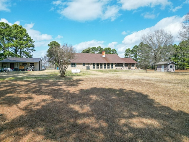 view of front of house with a chimney, a front lawn, and an outdoor structure