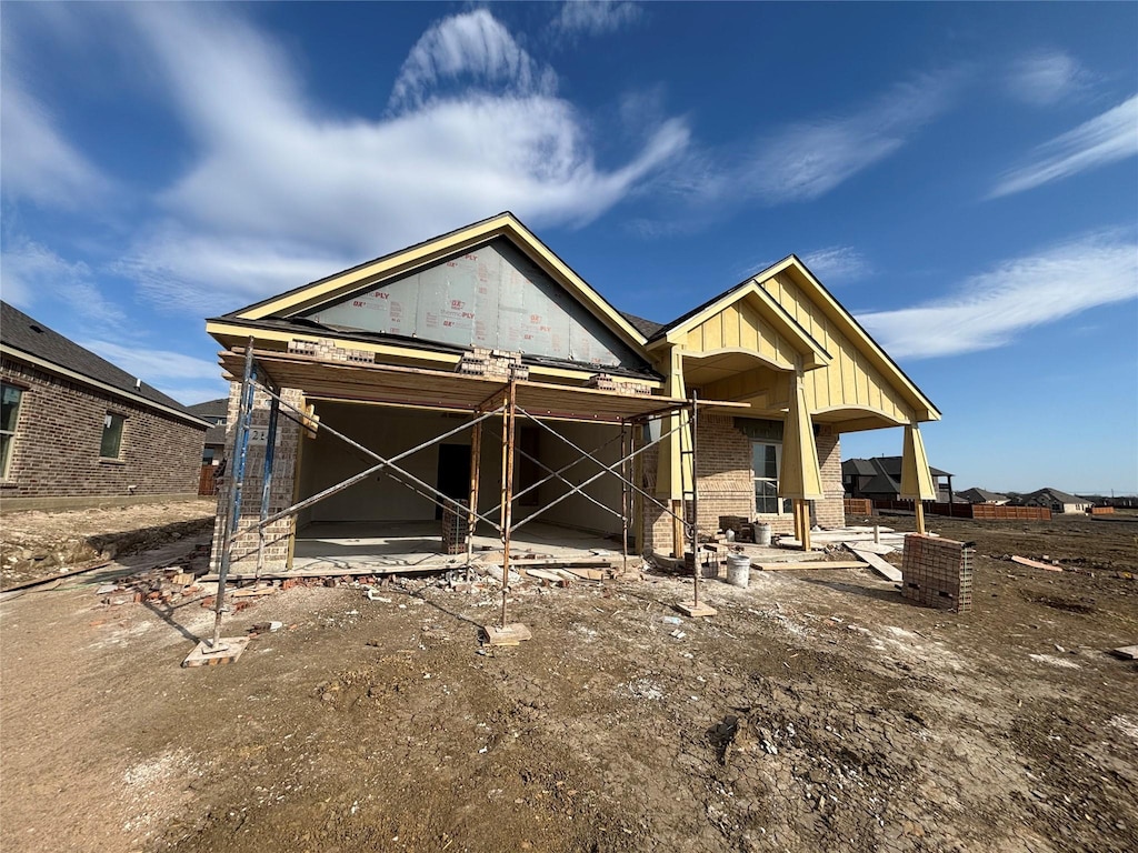 view of front facade featuring brick siding, board and batten siding, and a patio area