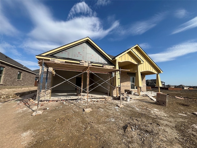 view of front facade featuring brick siding, board and batten siding, and a patio area