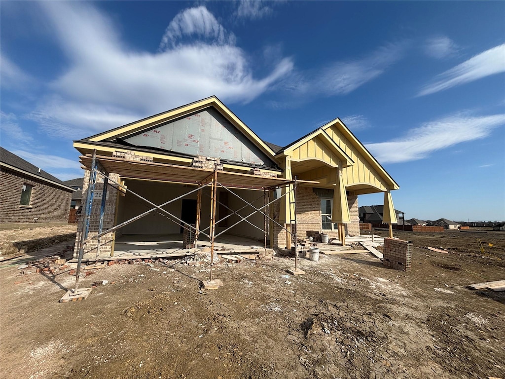 view of front of property with brick siding, board and batten siding, and a patio