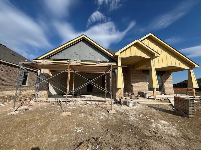 back of property featuring board and batten siding, brick siding, and a patio