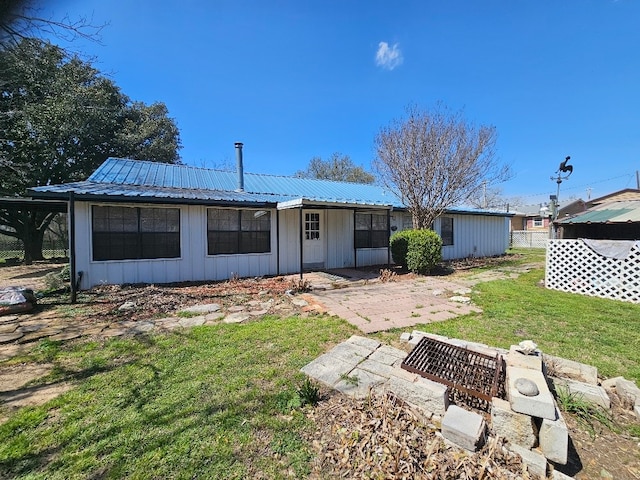 back of house featuring a lawn, board and batten siding, and metal roof