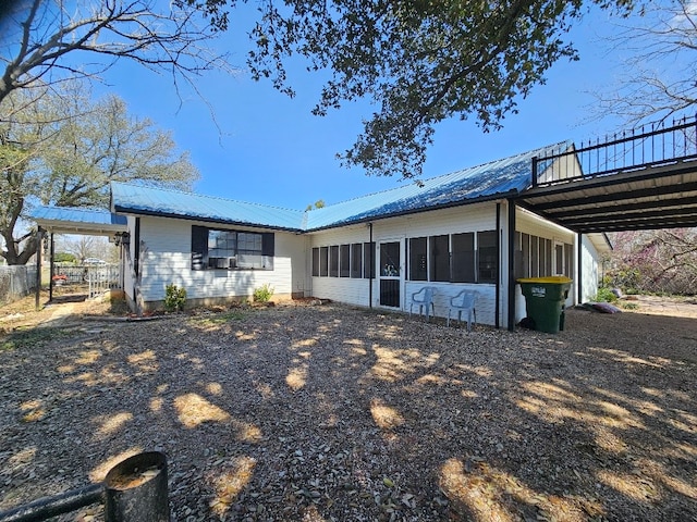 back of house with a carport, a sunroom, and metal roof