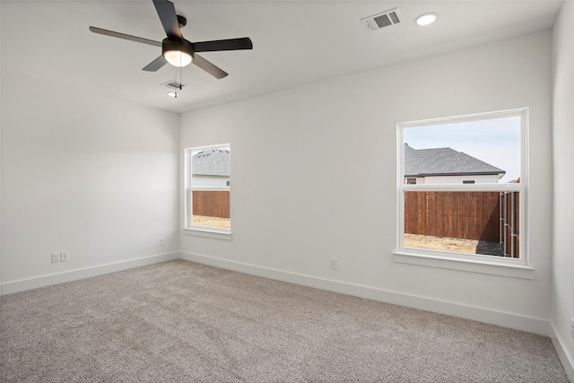 unfurnished room with carpet floors, visible vents, baseboards, and a ceiling fan