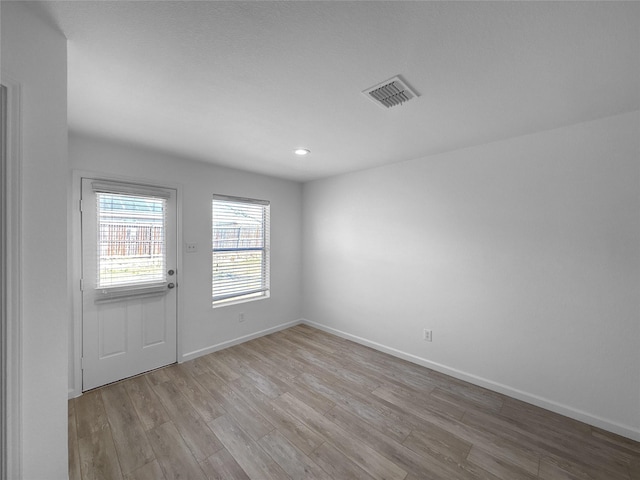 empty room featuring wood finished floors, visible vents, and baseboards