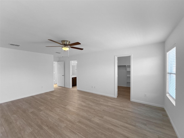 unfurnished room featuring light wood-style floors, visible vents, baseboards, and a ceiling fan