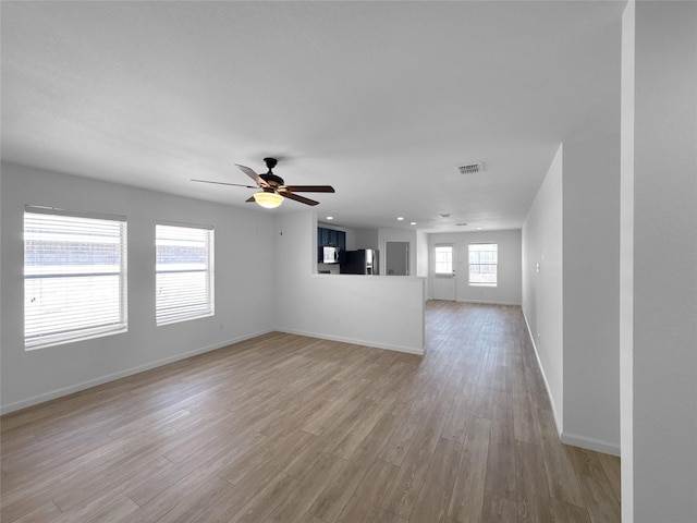 unfurnished living room featuring a ceiling fan, visible vents, light wood-style flooring, and baseboards