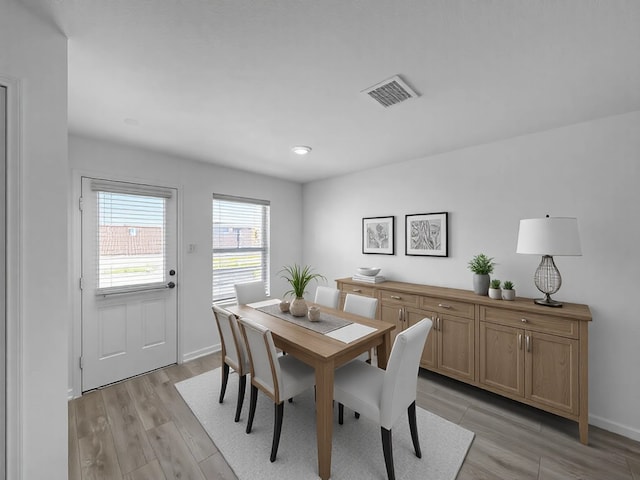 dining room featuring baseboards, visible vents, and light wood finished floors