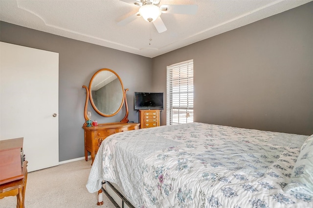 bedroom with light carpet, baseboards, a ceiling fan, and a textured ceiling