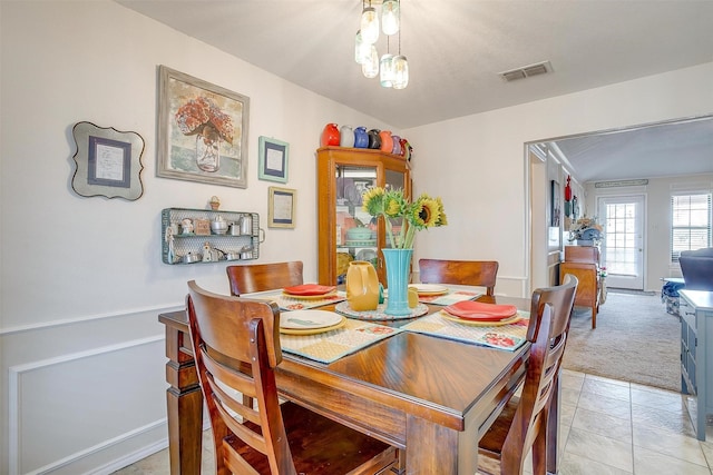 dining room with a chandelier, visible vents, light carpet, and light tile patterned floors